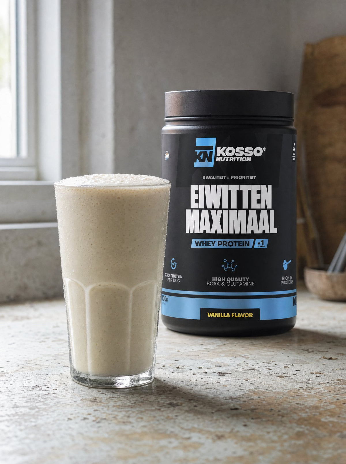 Glas vanilleshake met koude melk op een aanrecht, met de pot Eiwitten Maximaal erachter
