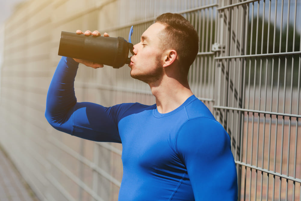 jonge sporter drinkt pre workout voordat hij begint met sporten